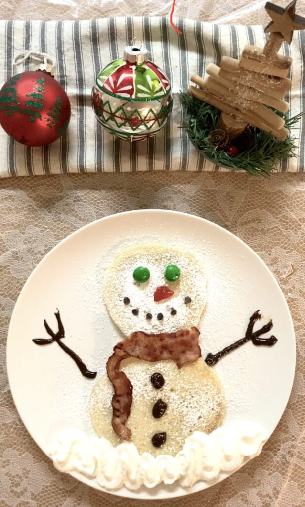 Snowman pancake with powdered sugar and candy decorations