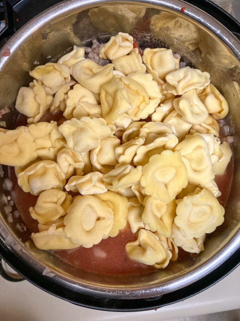 Tortellini being added to the Instant Pot.