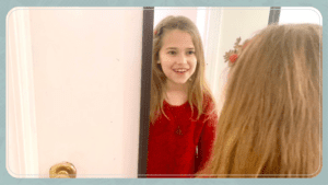 little girl smiling in front of mirror