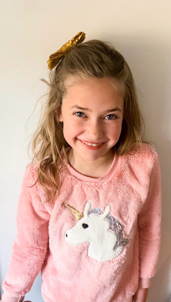 Preteen girl in Three Little Peas unicorn sweater