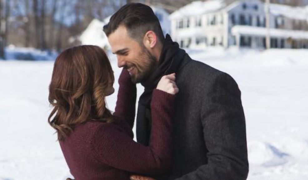 A man and woman hug in the snow in front of a huge mansion in the holiday romance movie The Spirit of Christmas