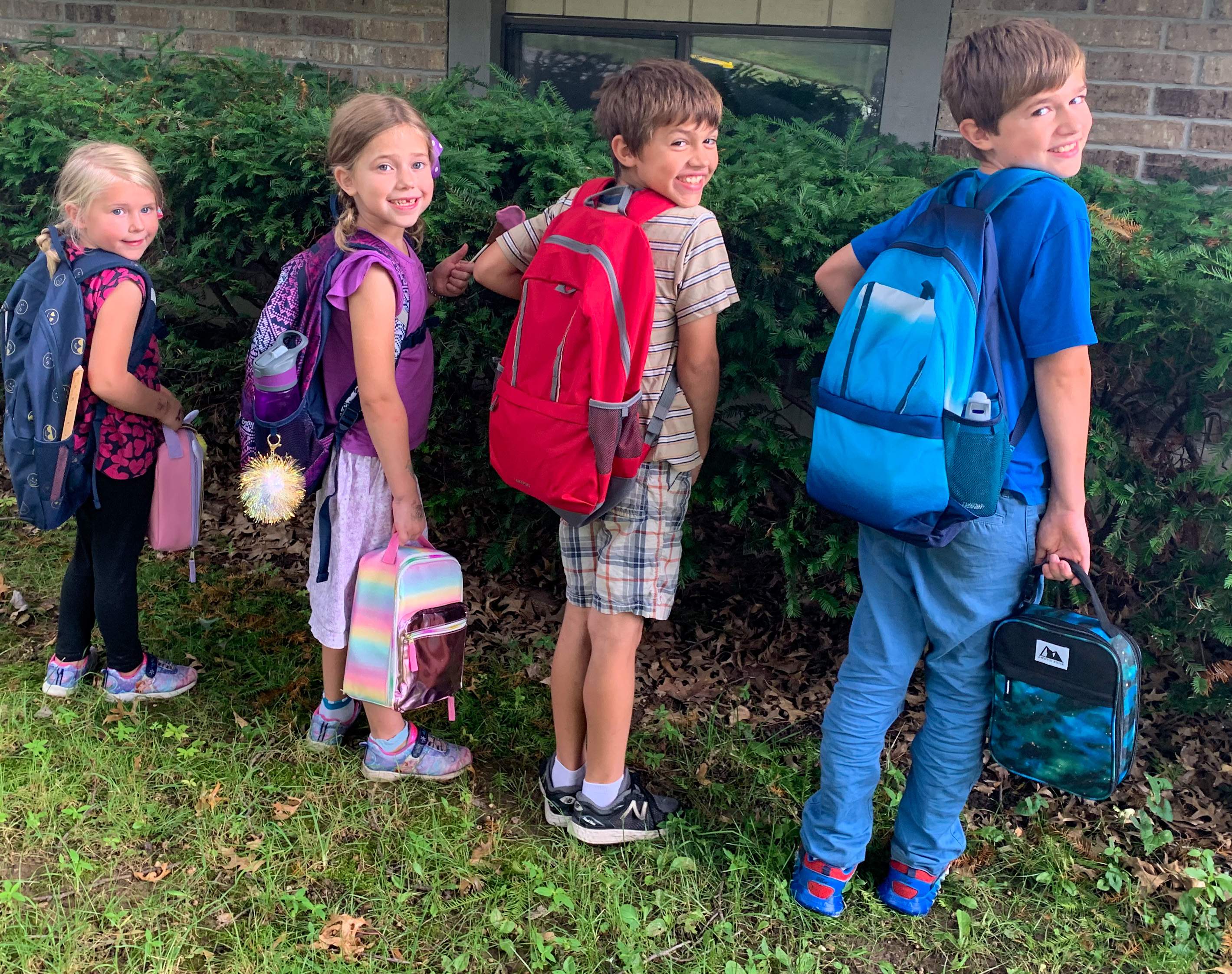 four children with new backpacks and lunchboxes for homeschool